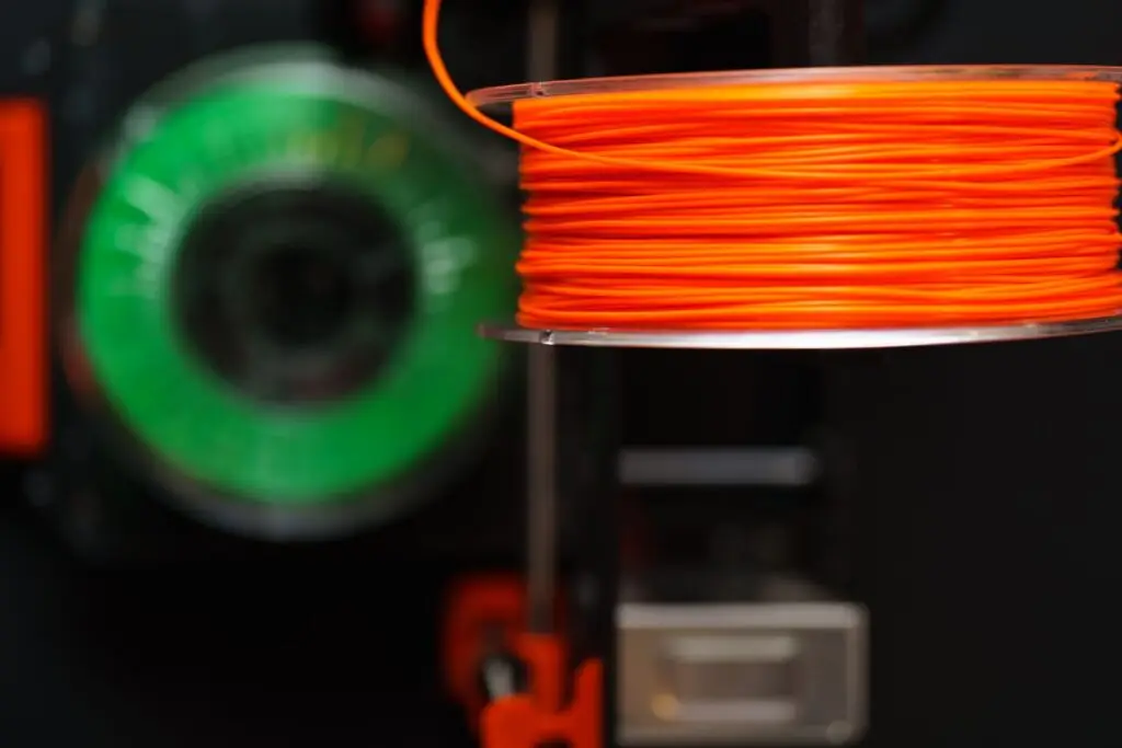 Bright orange filament spool feeding a 3D printer